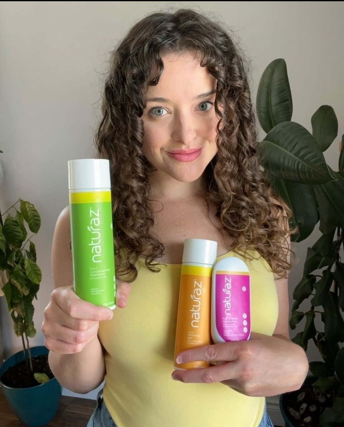 Woman holding the moisture burst system which consists of the shampoo, hair & scalp moisturizer and curl defining gel